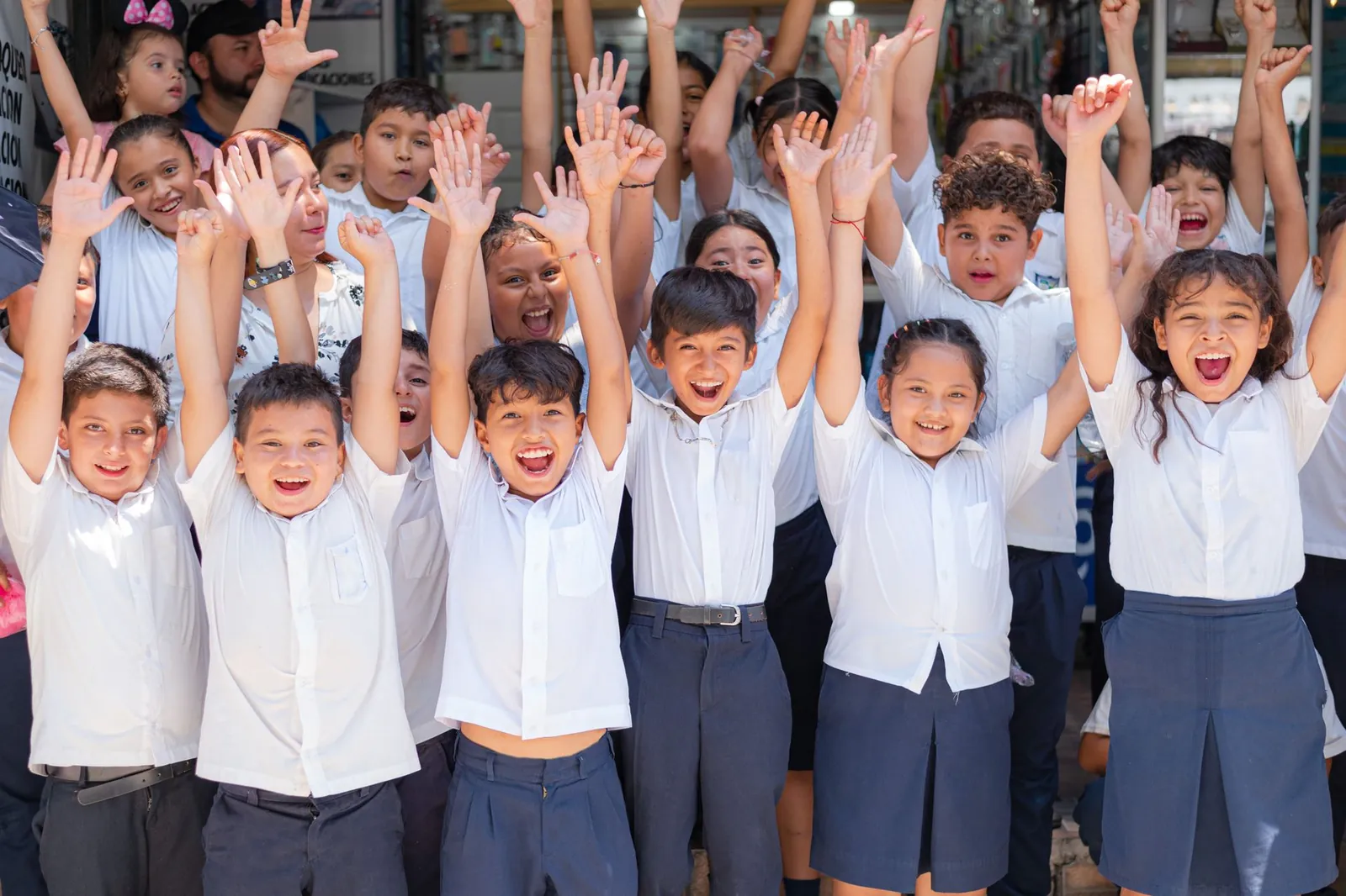 Niños de básica con uniforme celebrando en el patio; guía del Plan de Gestión de Convivencia Escolar