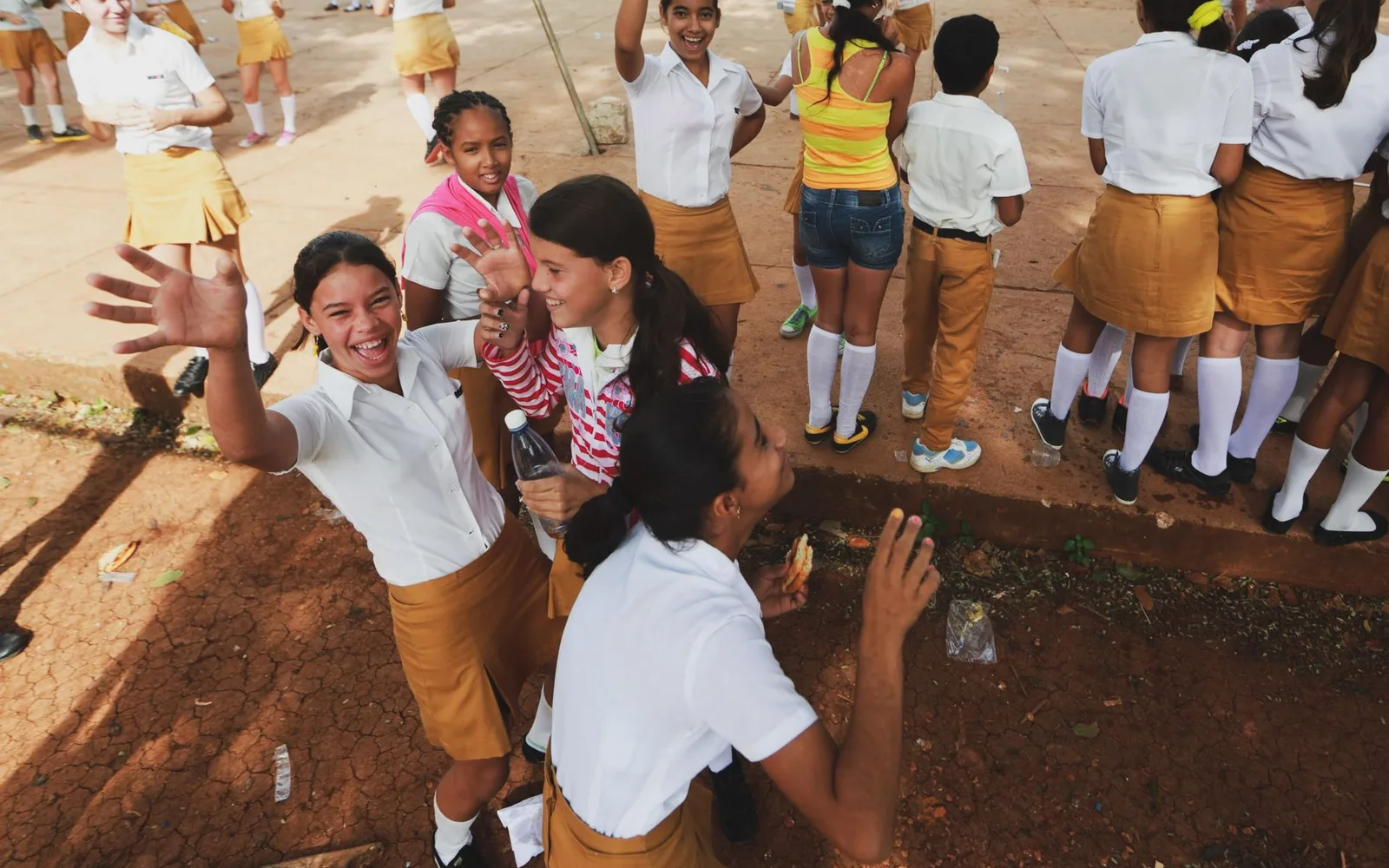 Niños con uniforme saludando a la cámara en el patio del colegio; guía del Día de la Convivencia Escolar